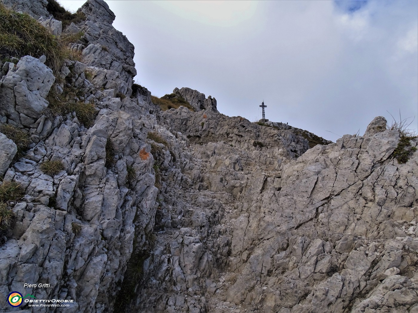 31 Salendo tra roccette spunta la croce del Resegone.JPG